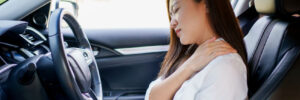 Young woman gripping her shoulder in pain after a car accident engaged her seat belt and locked into place